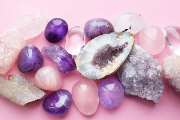 Beautiful gemstones,  geode amethyst and druses of natural purple mineral amethyst on a pink background. Amethysts and rose quartz. Large crystals of semi-precious stones.