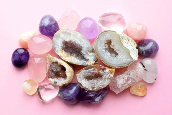 Beautiful gemstones,  geode amethyst and druses of natural purple mineral amethyst on a pink background. Amethysts and rose quartz. Large crystals of semi-precious stones.