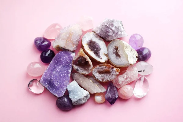 Beautiful gemstones,  geode amethyst and druses of natural purple mineral amethyst on a pink background. Amethysts and rose quartz. Large crystals of semi-precious stones.