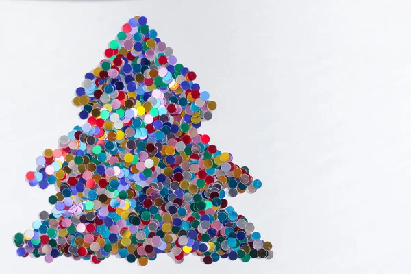 Silueta de un árbol de Navidad hecho de confeti brillante colorido sobre un fondo blanco —  Fotos de Stock