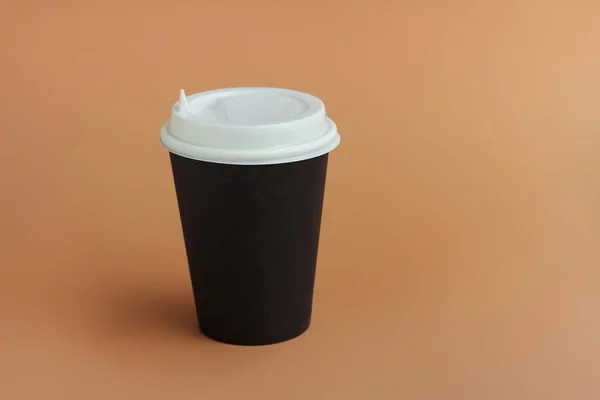 paper Cup with lid for coffee or hot drinks with you on a brown background.