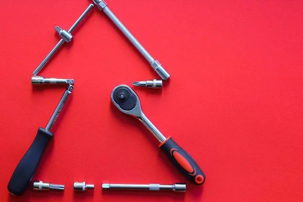 Kırmızı arka planda inşaat aletlerinden yapılmış Noel ağacı. Araba atölyesi için yılbaşı konsepti. Düz konum, boşluk kopyala, üst görünüm