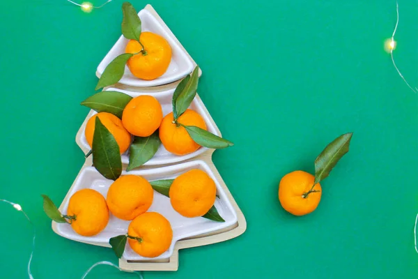 Yeşil arka planda Noel ağacı şeklinde mandalinalar. Noel yemekleri arka planı, en iyi manzara. Eğlenceli bir Noel ağacı.