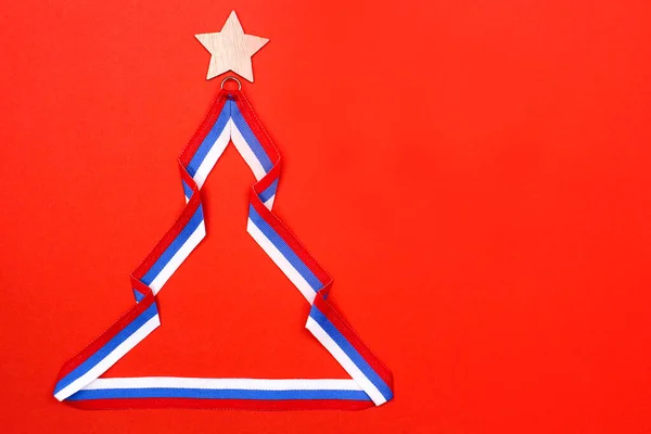 Weihnachtsbaum aus Band in der Farbe der russischen Flagge auf rotem Hintergrund. — Stockfoto