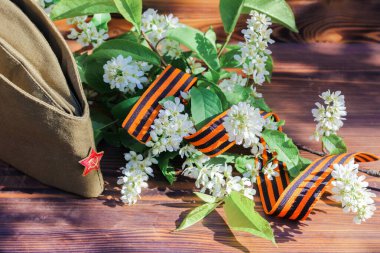 9 Mayıs, Bayram Zafer Günü. George kurdele, bahar çiçekleri ve askeri şapka. Boşluğu kopyala