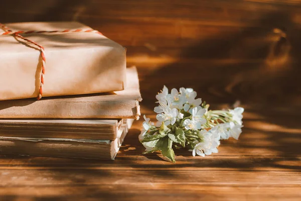 a stack of old books on a wooden background with a sprig of a flowering tree. the concept of memorabilia and historical notes