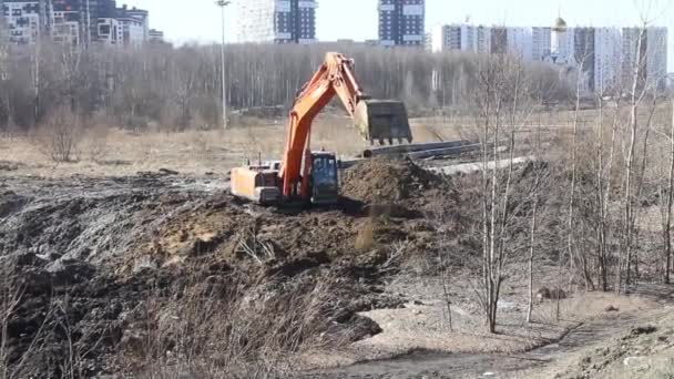 Russland, Sankt Petersburg 3. April 2019 Ein Bagger gräbt ein Loch in die frühlingshafte weiche Erde. Vorbereitung auf den Bau oder die Verlegung von Kommunikationsanlagen — Stockvideo