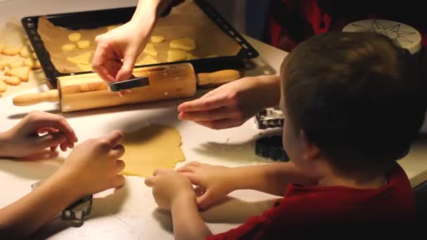 Zelfgemaakte koekjes koken. Mam en kinderen snijden koekjes uit het deeg met mallen. kerststemming — Stockvideo
