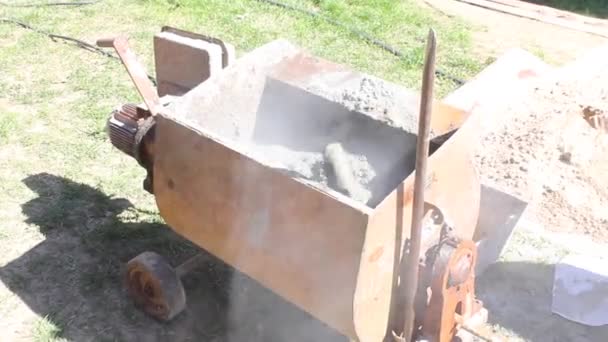 Mélange de mortier de béton dans une bétonnière. ajouter du ciment et du sable à l'eau — Video