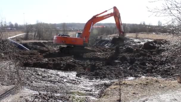 Росія, Санкт-Петербург, 3 квітня 2019 року екскаватор викопав яму у весняній м'якій землі. підготовка до будівництва або встановлення зв "язку.. — стокове відео