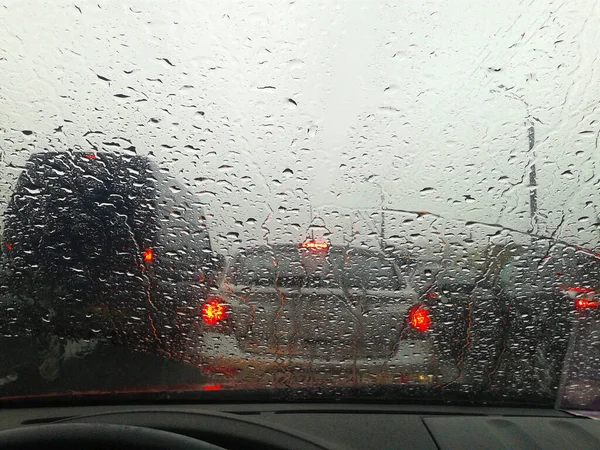 Street in the heavy rain. Water drops or rain in front of mirror of car on road or street