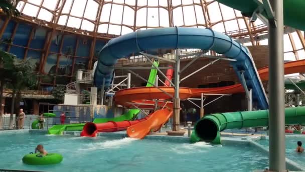 Russia, Saint Petersburg May 20, 2021: a teenage girl rides a plastic water slide on an inflated cushion in an indoor pool. visit to the water park all year round. water activities — Stock Video