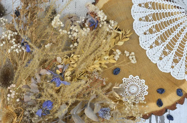 Kurumuş yapraklardan, mavi ve beyaz çiçeklerden, otlardan, kurutulmuş eriklerden ve eski örülmüş peçeteden yapılmış Boho dekorasyonu. Ahşap arkaplan.
