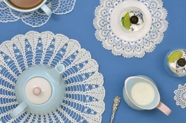 Üst manzara, eşsiz durumlar için zarif masa dekorasyonu. İki meyve tatlısı, çay demliği, sütlü mavi sürahi ve çok büyük bir fincan çay ile mavi çay zamanı..