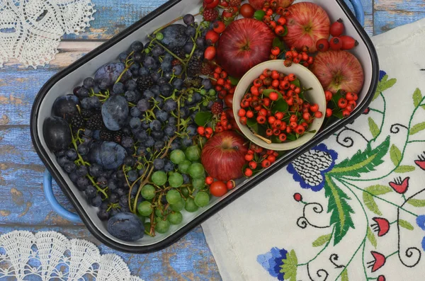 Kırmızı ve koyu mavi meyveli kızartma tavası reçel yapmaya hazır. Kırsal dekorasyonlar: bölgesel, Kashubiya nakışı ve işlemeli altlıklar ve ahşap arka plan.