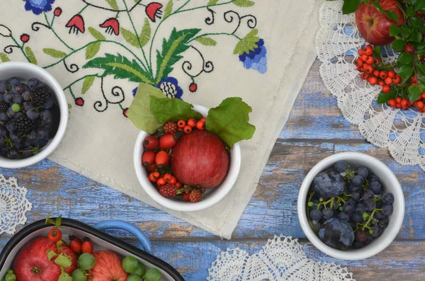 Kırmızı elmalı, mavi erikli, koyu üzümlü, rustik, tığ işi ve bölgesel, Kashubian işlemeli peçeteleri mavi mutfak masasına. Yemeye ya da muhafaza edilmeye hazır hasat et.