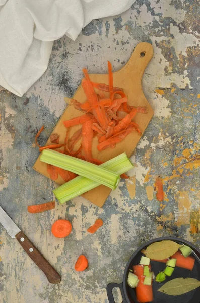 Bir doğrama tahtasında havuç kabukları (bio-atık), bıçak ve keten mutfak örtüsü; üst görünüm mutfak masası; akşam yemeği hazırlama hazırlıkları (örneğin). 