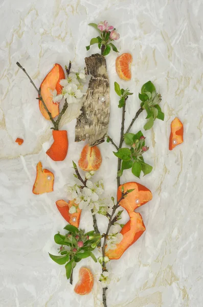 İlginç, soyut ve eğlenceli dekorasyon dallar, yapraklar, beyaz çiçekler, kabuk ve atık: mandalina, mandalina kabuğu parçaları.