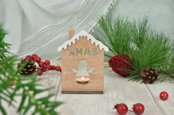 Noel süsü ve küçük kış evi şamdan olarak kullanılıyor. Evergreen kırmızı böğürtlen ve koni dalları. Nane arkaplanı.