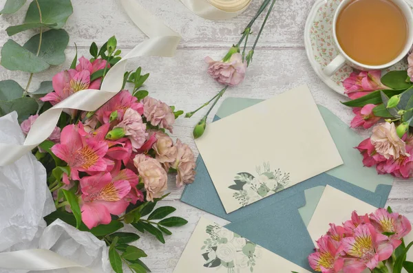 İçini doldurmak için içi boş kağıt, bir buket frezya ve okaliptüs ile karanfiller, bir fincan çay. Blogcu için kadınsı dekorasyon.