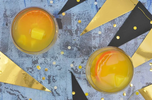Mandalina dilimleri ve mangolu sarı ve turuncu kokteyller. Mavi arka planda altın madalyalar. Hayat etkinliği, parti, yeni yıl arifesi, isim günü ya da yıldönümü..