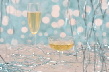 Parti: Şampanya bardakları ya da mavi melek saçlarıyla süslenmiş beyaz şarap. Arkaplanda Bokeh.