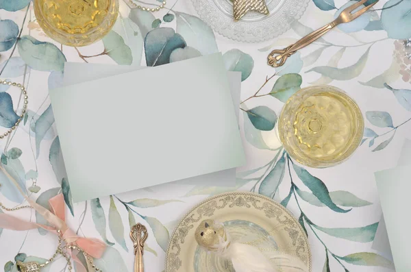 İki bardak altın içecekle şık bir dekorasyon, zarif çatallar, boyanmış yapraklar ve nane şekeri, ortada boş bir kağıt. Dileklerle doldurulacak kart, tebrikler ya da sevgililer günü için bir davetiye, düğün, doğum günü, yıldönümü, parti.