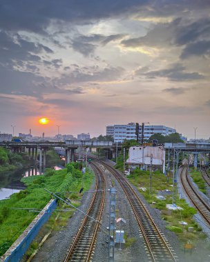 Chennai, Hindistan 'da üç demiryolu üzerinde muson bulutlarıyla güzel bir gün batımı..