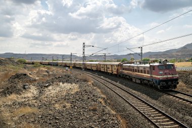 Daundaj, Maharashtra, Hindistan-18 Mayıs 2025: Bir yolcu treni Pune-Miraj demiryolu hattının manzaralı bir bölümünden geçiyor.