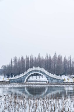 Gri kış gökyüzü ve donmuş göl ve geleneksel antik köprü