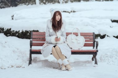 Bir kız dışarıda, ormanda, yoğun kar altında. 