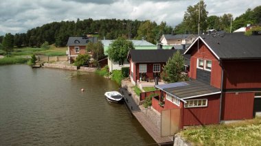 Bir nehir, bir tekne, ağaçların arasında İskandinav tarzı evler..