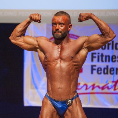 Erkek vücut geliştirmeci onun fiziksel göstermek için kasları şişiriyor