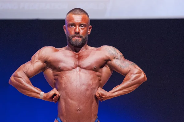 Male bodybuilder flexes his muscles to show his physique — Stock Photo, Image