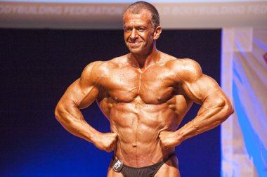 Erkek vücut geliştirmeci kasları şişiriyor ve onun en iyi fiziksel gösterir