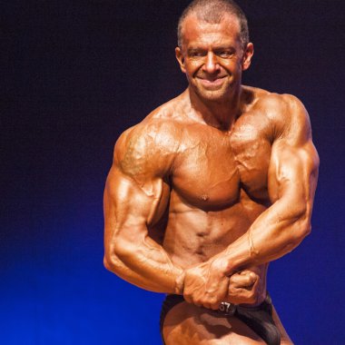 Erkek vücut geliştirmeci kasları şişiriyor ve onun en iyi fiziksel gösterir