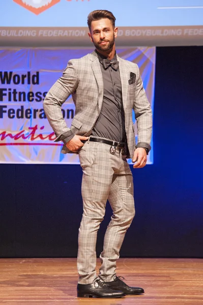 Male physique model shows his best in suit on stage