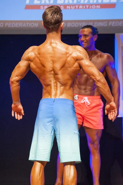 Modelo de fitness masculino muestra su físico en traje de baño om etapa —  Fotos de Stock