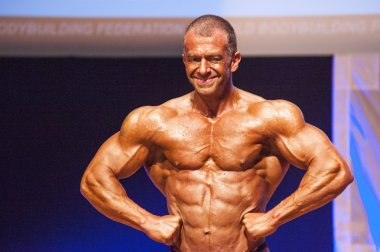 Erkek vücut geliştirmeci kasları şişiriyor ve onun en iyi fiziksel gösterir