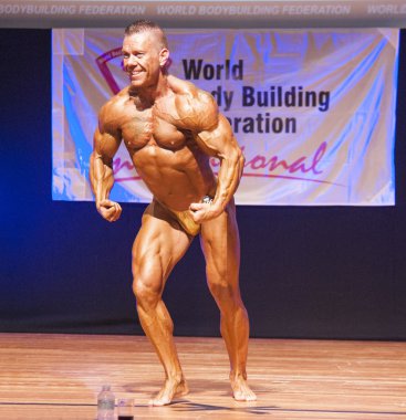 Erkek vücut geliştirmeci kasları şişiriyor ve onun en iyi fiziksel gösterir