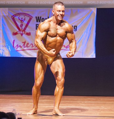 Erkek vücut geliştirmeci kasları şişiriyor ve onun en iyi fiziksel gösterir