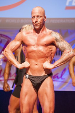 Erkek vücut geliştirmeci kasları şişiriyor ve onun en iyi fiziksel gösterir