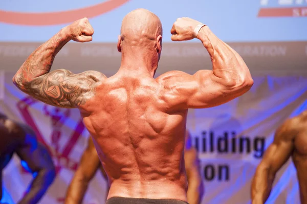 Erkek vücut geliştirmeci kasları şişiriyor ve onun en iyi fiziksel gösterir