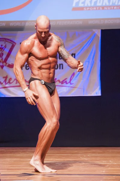 Erkek vücut geliştirmeci kasları şişiriyor ve onun en iyi fiziksel gösterir