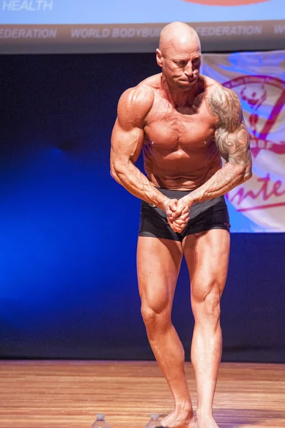 Männlicher Bodybuilder zeigt sich bei Meisterschaft auf der Bühne von seiner besten Seite — Stockfoto