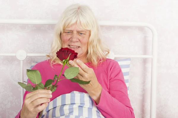 Šťastná žena v posteli s růží — Stock fotografie