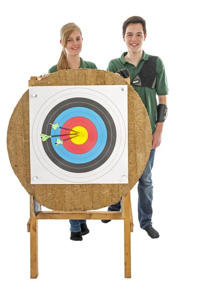 Girl and boy standing behind archery target — Stock Photo, Image
