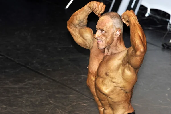 Male bodybuilding contestant showing his double biceps — Stock Photo, Image