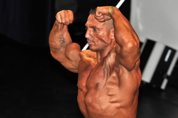 Άρρεν bodybuilding αγωνιζόμενος προβολή του θέτουν διπλά δικέφαλου — Φωτογραφία Αρχείου