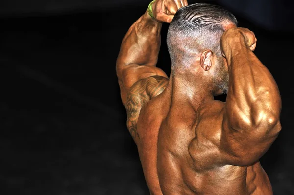 Představují mužský kulturistika soutěžící dělá zpět dvojitý biceps — Stock fotografie